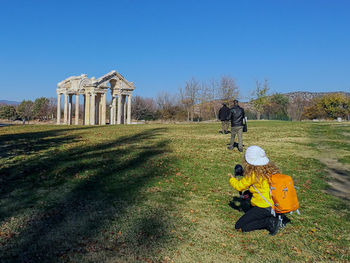 Rear view of people on field against clear sky