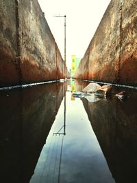 Canal by wall against sky