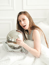 Portrait of young woman sitting on bed at home