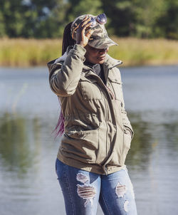 Portrait of young woman standing by lake