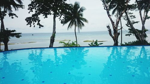 Swimming pool by sea against sky
