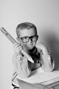 Portrait of cute boy holding pencil while sitting on desk at home