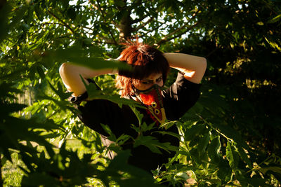 Portrait of young woman wearing mask standing by tree