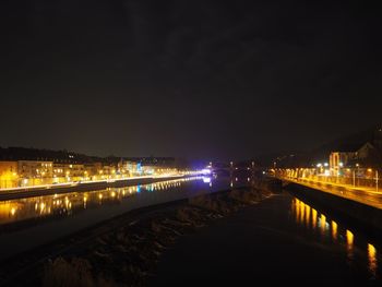 Illuminated bridge over river against sky at night