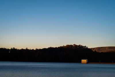 Scenic view of lake against clear sky at sunset