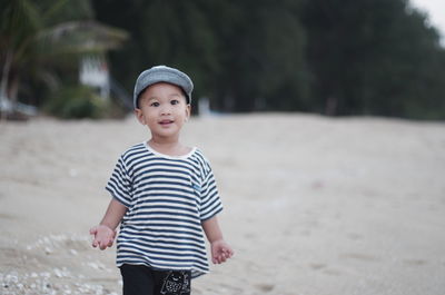 Portrait of cute boy standing at beach