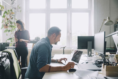 Side view businessman using laptop at desk in creative office