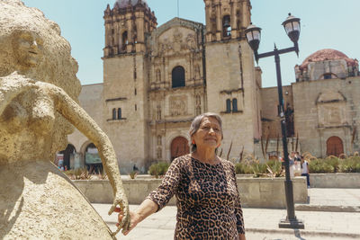 Portrait of woman standing against historic building