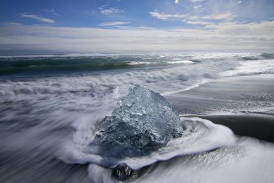 Waves splashing on sea against sky