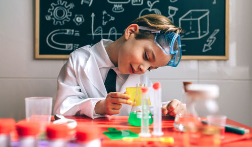 Cute boy examining chemical in classroom