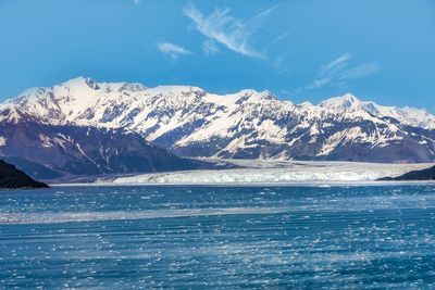 Scenic view of sea and snowcapped mountains against blue sky