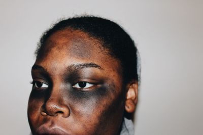 Close-up of woman with make-up looking away by white wall during halloween