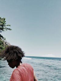 Rear view of a little girl by sea against clear sky