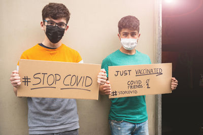 Portrait of friends standing against wall