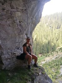 Portrait of mature woman sitting by rock formation on mountain