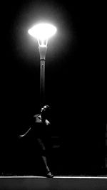Man holding illuminated street light at night