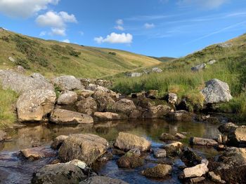 Scenic view of stream by rocks against sky