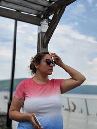 Mid adult woman wearing sunglasses standing against sky