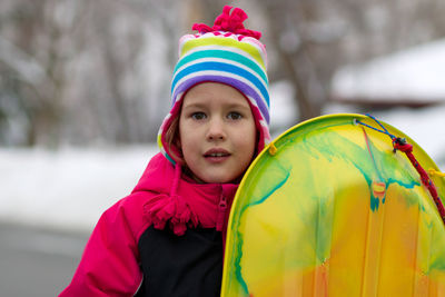 Portrait of cute girl holding yellow sled