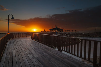 Pier over sea against sky during sunset