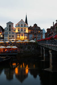 Bridge over river by buildings against sky in city