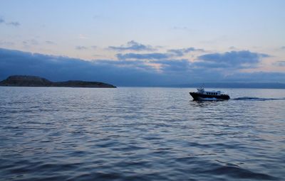 Boat sailing in sea against sky during sunset
