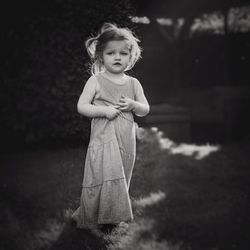 Portrait of cute girl standing on grassy field at park