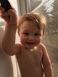 Portrait of shirtless boy by door