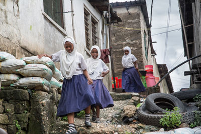 Girls in uniform walking amidst houses at village