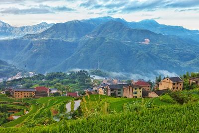Houses on field by mountains against sky