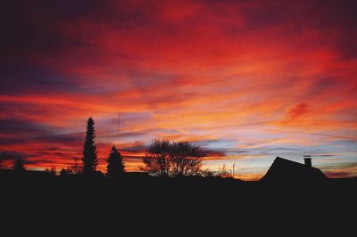 Low angle view of silhouette trees against dramatic sky