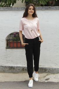 Portrait of smiling young woman standing against wall