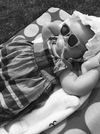 High angle view of baby girl wearing sunglasses while lying on bed