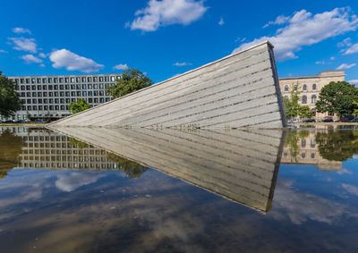 Reflection of buildings in lake against blue sky