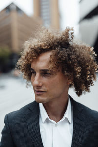 Businessman with brown curly hair looking away