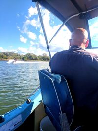 Rear view of man sitting in boat against sky