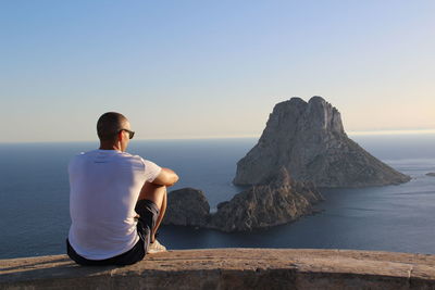 Woman sitting on cliff by sea