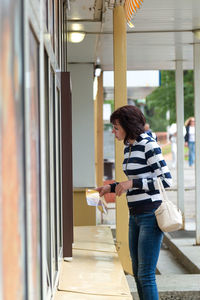 Adult woman pays the seller at the kiosk for the purchase of groceries.