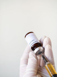 Close-up of hand holding bottle against white background