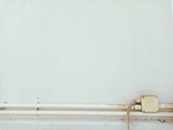 Close-up of metal railing against white wall