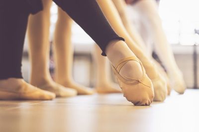 A close up photo of ballet shoes in a row, photo is taken at a dance studio