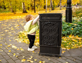 Cute little baby throws trash into trash can in autumn park. instilling cultural norms from birth