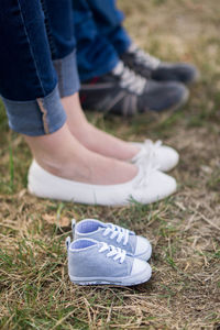 Low section of people standing by baby booties on grass