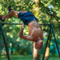 Full length of shirtless man exercising in park