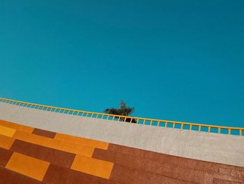 Wall by swimming pool against clear blue sky