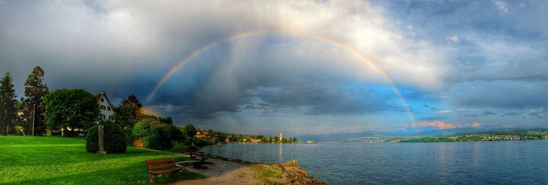 Scenic view of rainbow over trees against sky