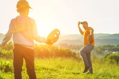 Side view of woman with arms outstretched standing on field