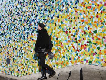 Rear view of woman standing on multi colored umbrella