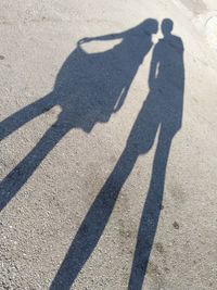 Shadow of man with umbrella standing on road