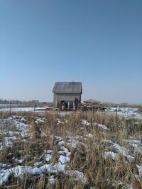 House on snow covered field against clear sky